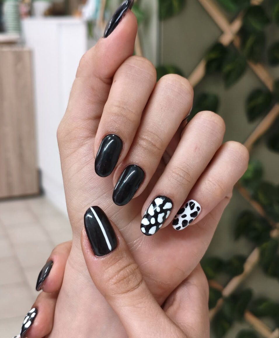 Black gel manicure with white animal-print accent nails