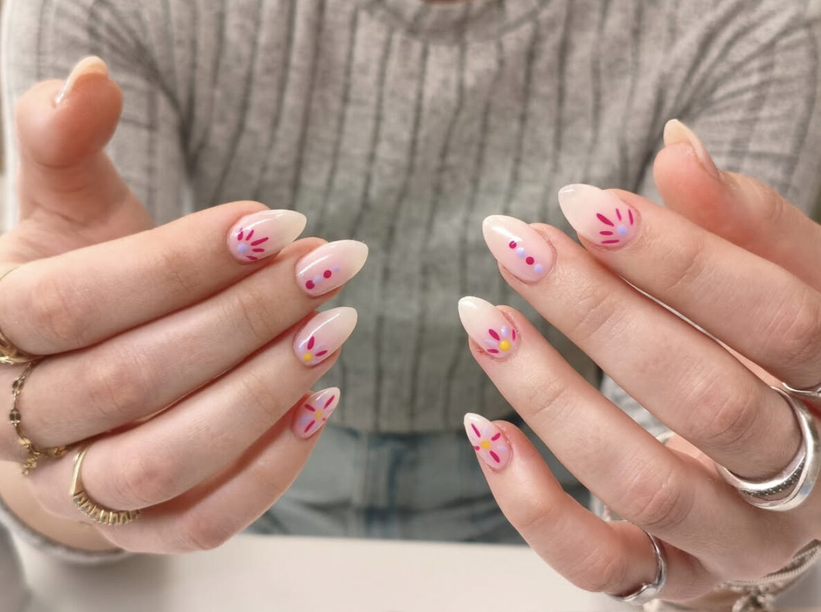 Nude almond nails with minimalist hand-painted pink wildflower nail art