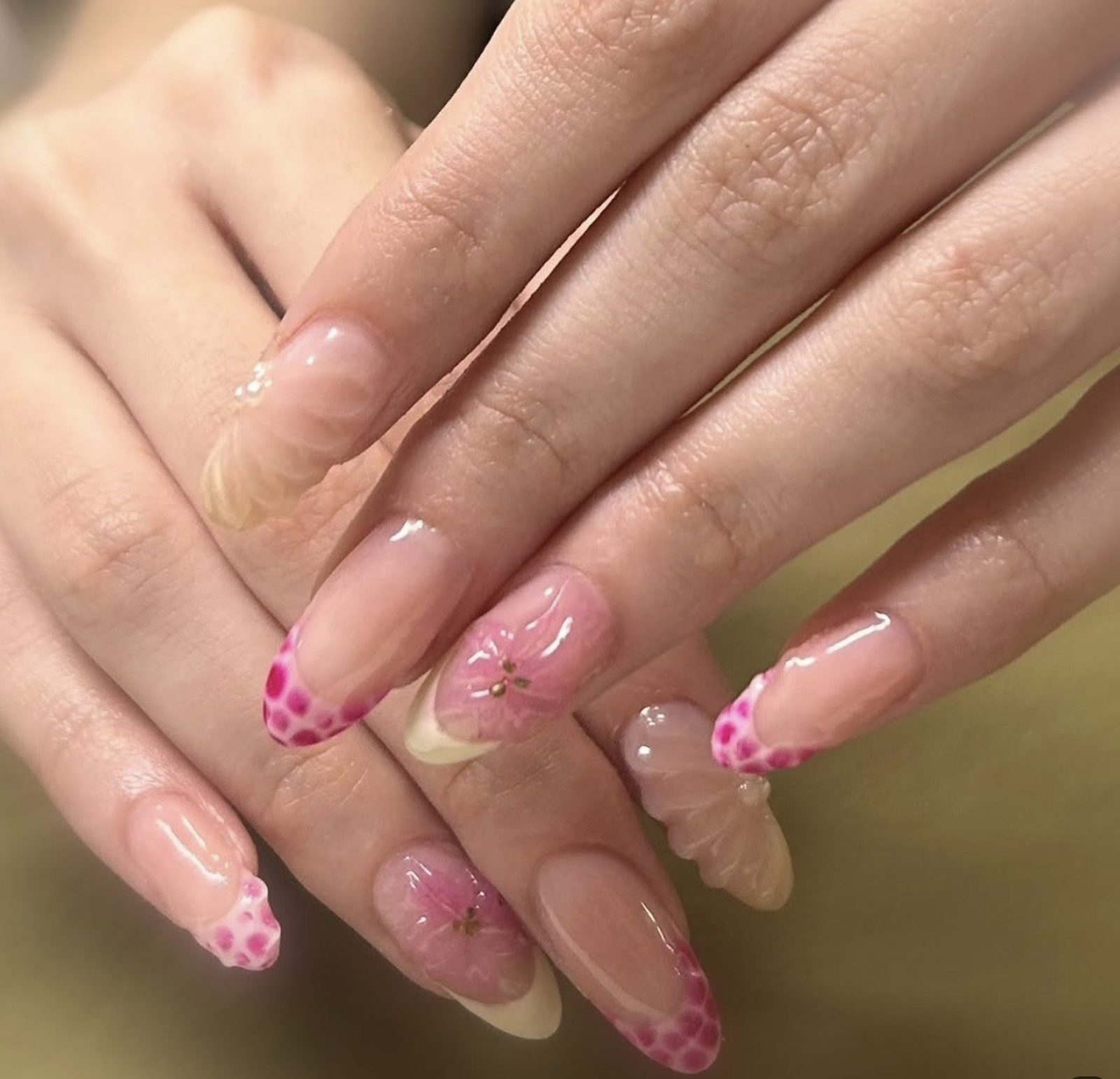Nude almond manicure with pink leopard French tips and hand-painted pink floral accent nails